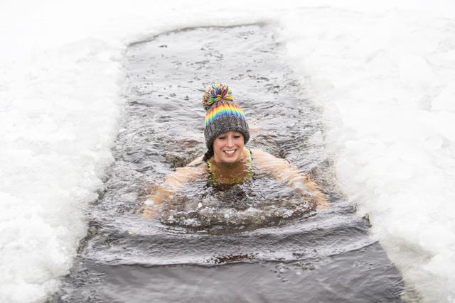Alice Goodridge swims in Loch Insh after using an axe and a sledgehammer to create a channel through the ice 