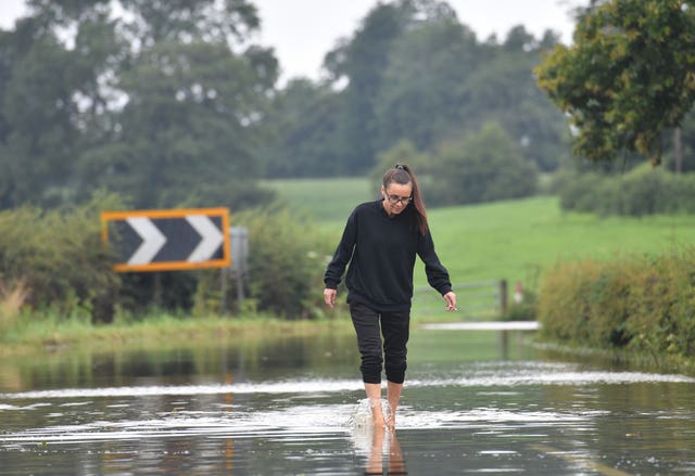 A woman makes her way along the flooded Bonis Hall Lane in Cheshire