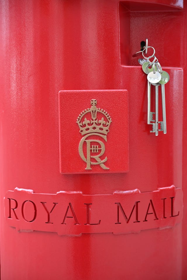 A close up of the King's cypher on a red postbox beside a set of keys to unlock it