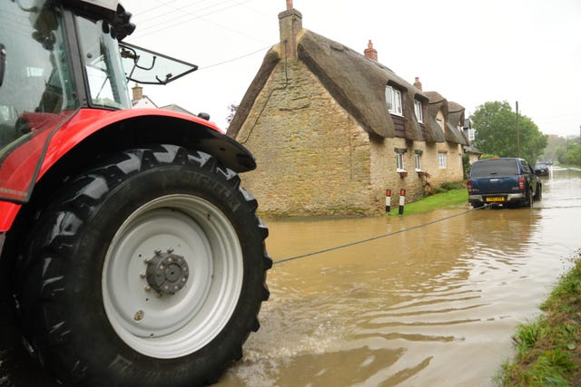 A tractor pulling a vehicle stuck in flood water in Grendon, Northamptonshire