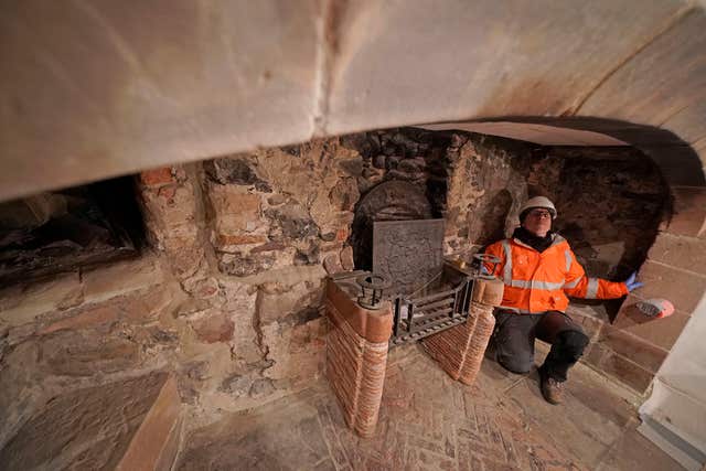 A workman works on a fireplace (Owen Humphreys/PA)