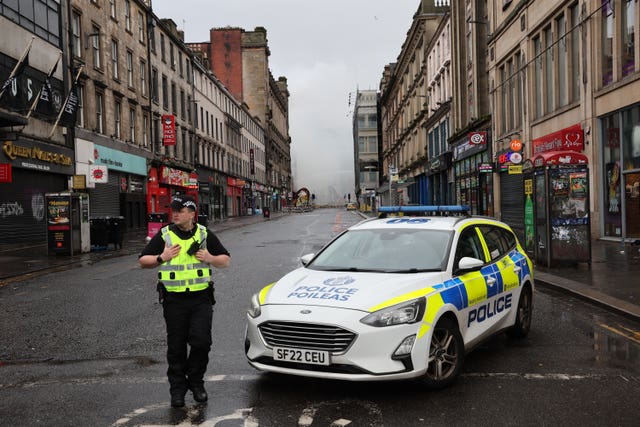 A police officer standing next to a police car at the scene