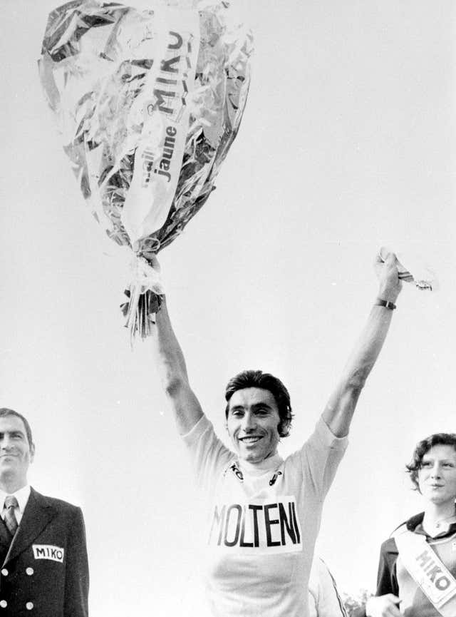 Eddy Merckx, holding flowers in his right hand, raises both arms after winning the Tour de France
