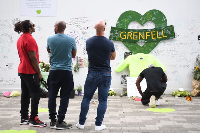 People at the Grenfell Memorial Community Mosaic at the base of the tower block