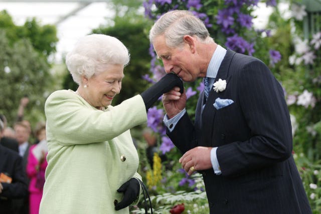 Charles, as the Prince of Wales, kisses his the gloved hand of his mother Queen Elizabeth II to greet her at the Chelsea Flower Show