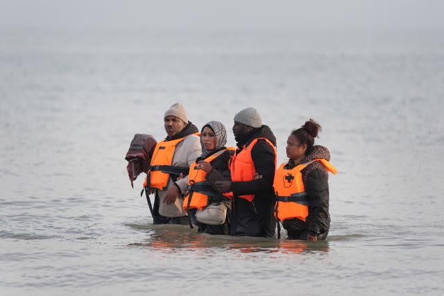 People thought to be migrants wade through the sea at Gravelines awaiting a boat