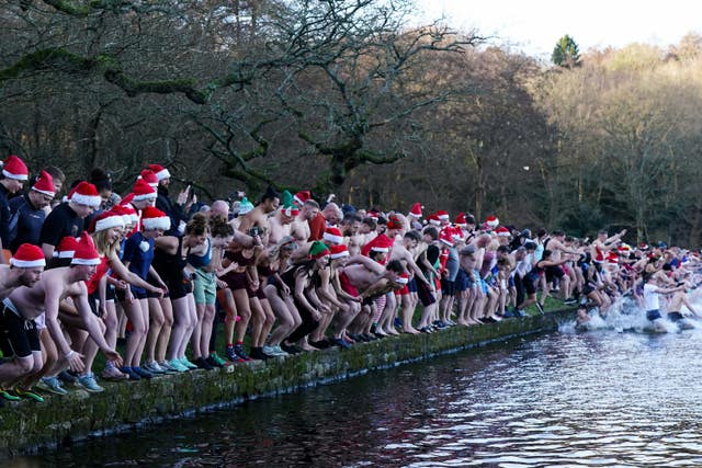 Swimmers perched on the edge of a lake in Blackroot Pool at Sutton Park getting ready to dive in