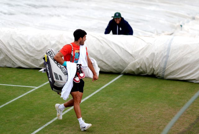 Defending champion Carlos Alcaraz walks off the practice courts on Sunday during a rain spell 