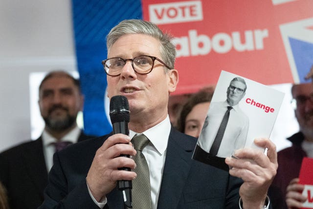 Sir Keir Starmer holding the Labour manifesto and speaking into a microphone