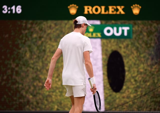 Jannik Sinner walks in front of the giant screen showing the ball is out