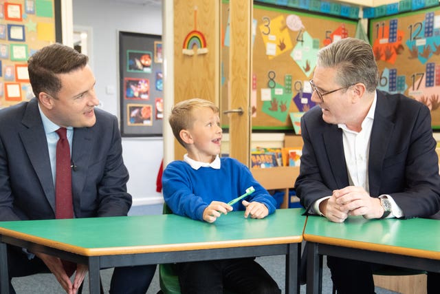 Sir Keir Starmer and shadow health secretary Wes Streeting in a school classroom with a boy holding toothbrush
