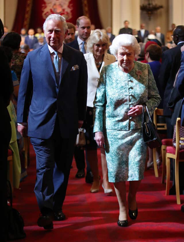 The Queen, accompanied by the Prince of Wales, arrives at the opening ceremony of the Commonwealth Heads of Government Meeting in Buckingham Palace, with the Duchess of Cornwall and Duke of Cambridge in the background. (Yui Mok/PA)