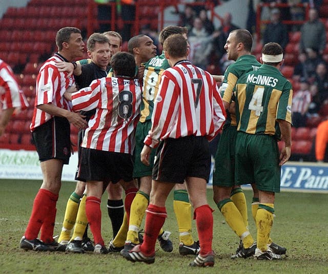 Referee Eddie Wolstenholme is caught in the middle of a melee during the 'Battle of Bramall Lane' in 2002