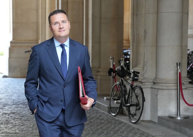 Wes Streeting walking with a red Government folder under his arm