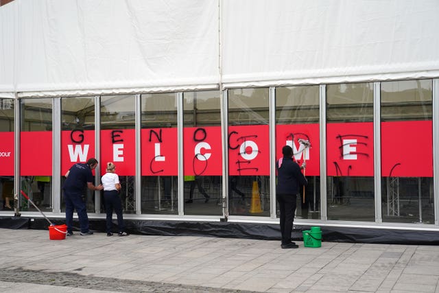 People removing graffiti sprayed by Youth Demand on the security check-in building at the Labour Party conference at the ACC in Liverpool