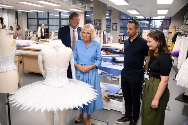 The Queen, in a blue dress, admires a ballet costume