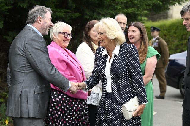 Camilla shakes hands with a man while meeting a number of dignitaries