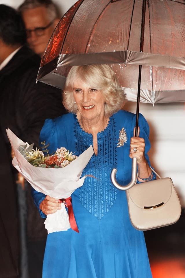 Camilla smiles beneath the umbrella