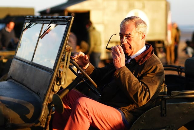 Nigel Farage removes his sunglasses as he sits in a vintage jeep at sunrise