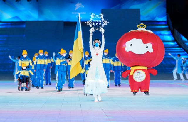 The Ukraine Paralympic team are led out onto the stage alongside Shuey Rhon Rhon, mascot of the Beijing 2022 Paralympic Winter Games
