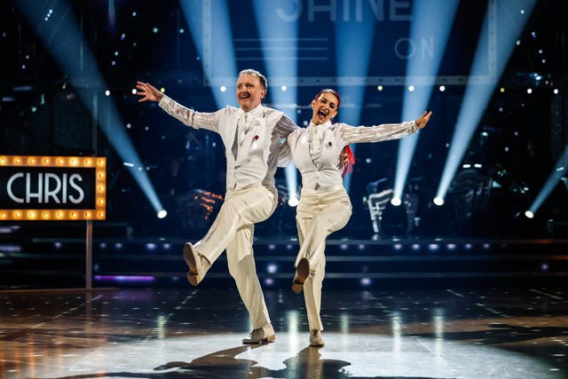 Buswell and McCausland kick their legs into the air in white suits