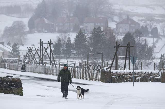 A man walks his dog through snow in Overwater, Cumbria (Owen Humphreys/PA)