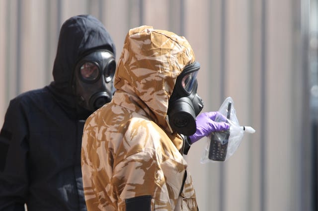 Investigators in chemical suits remove an item as they work behind screens erected in Rollestone Street, Salisbury, Wiltshire