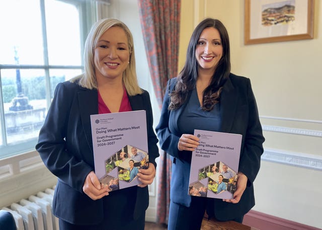 Michelle O'Neill and Emma Little-Pengelly smiling while holding copies of the draft programme for government