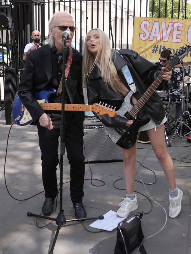 Brian Hyland and Ashleigh Harley playing guitars and singing outside Downing Street.