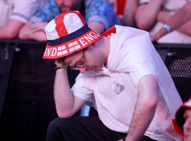 A man with an England hat holds his hand to his head