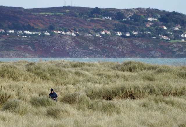 A woman goes for a walk in strong winds on Bull Island in Dublin as Storm Dudley makes its way over Ireland