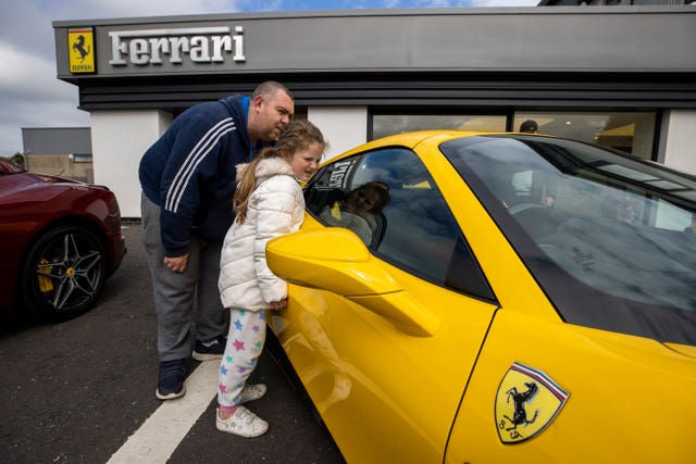 Neil Robinson and his daughter Miley look at Ferrari cars at the Charles Hurst dealership in Belfast (Liam McBurney/PA)