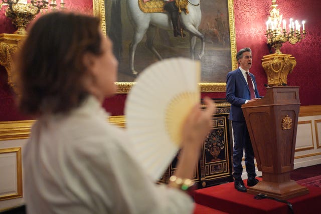 A woman uses a fan while watching an address by Ed Miliband