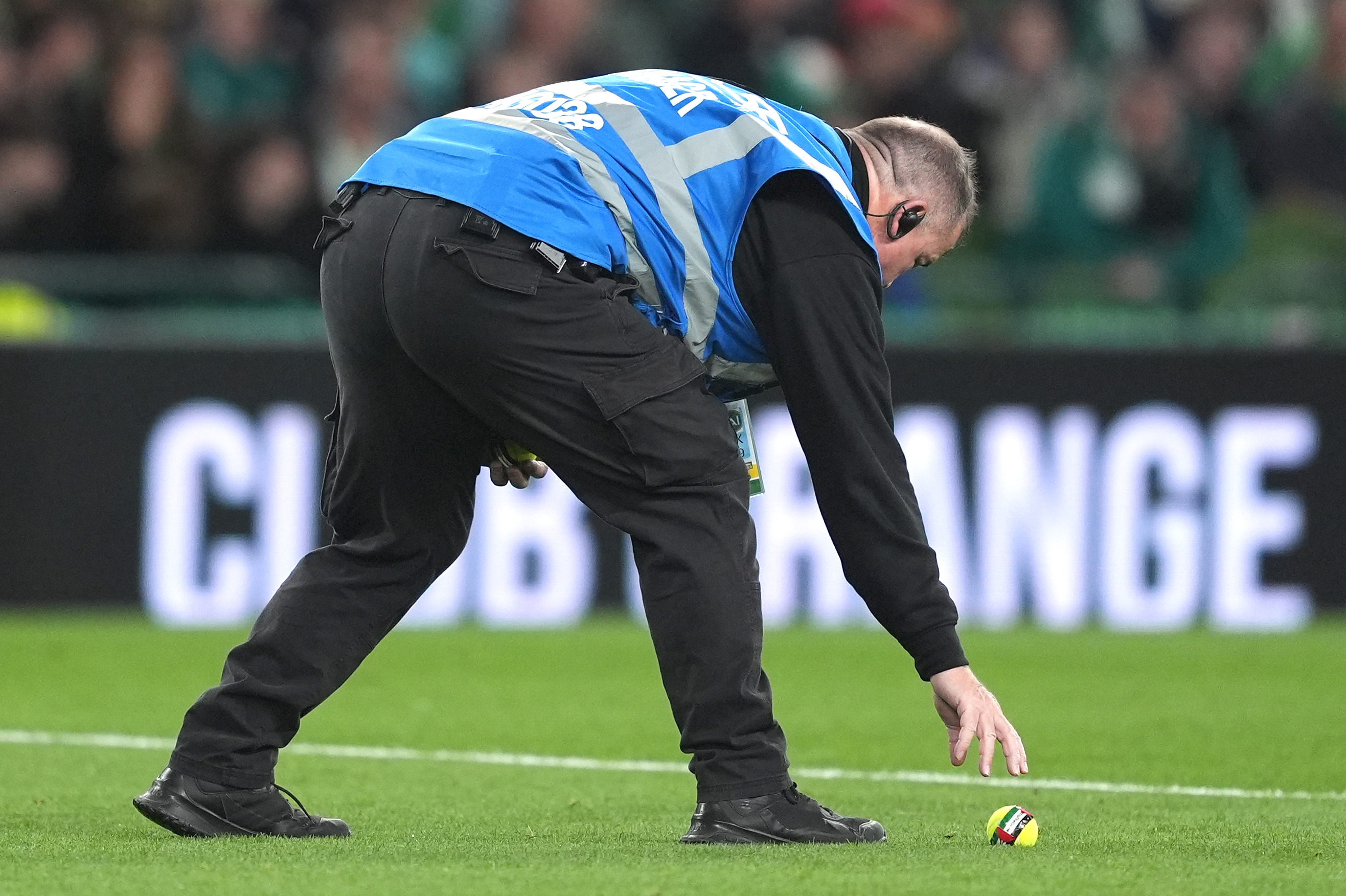 A steward removes a tennis ball from the pitch