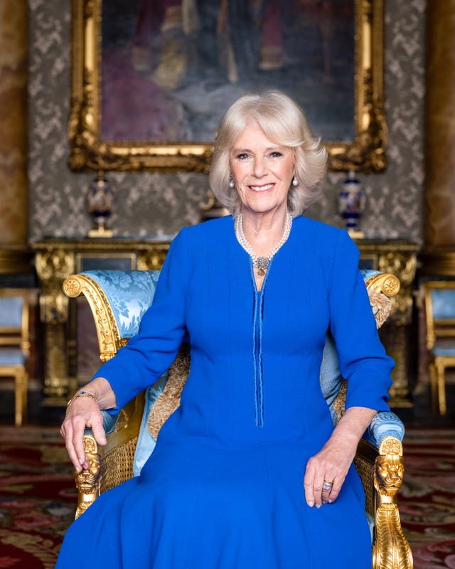 Camilla is wearing a blue wool crepe coat dress, designed by Fiona Clare, the late Queen’s pearl drop earrings set with a sapphire and ruby, and a pearl necklace from her private collection
