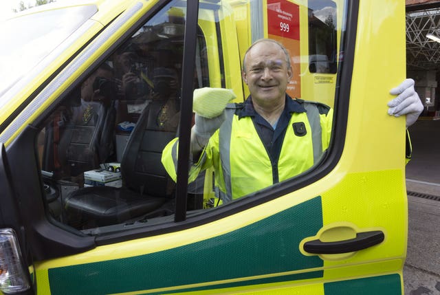 Sir Ed Davey looks through an ambulance window after cleaning the vehicle