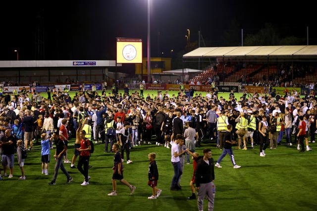 Crawley Town fans celebrate on the pitch at the end of the Carabao Cup second round win over Fulham