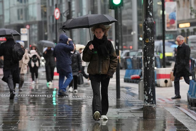 A person using an umbrella to shelter from the rain while walking in Shoreditch, London