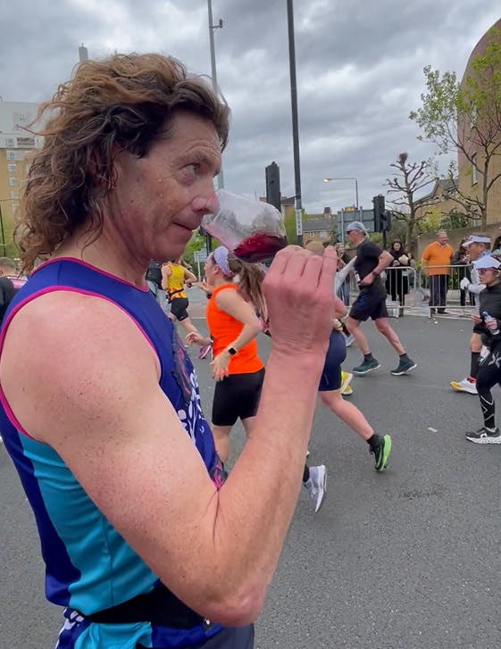 London Marathon runner holding and sipping glass of wine during his run