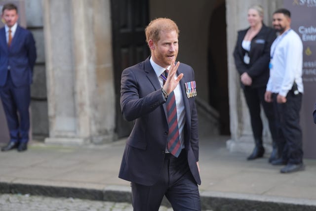 Harry walks along and waves with his right hand after leaving St Paul's Cathedral