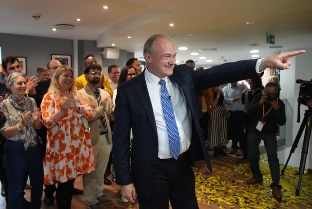 Sir Ed Davey points as supporters applaud and a photographer takes pictures of him