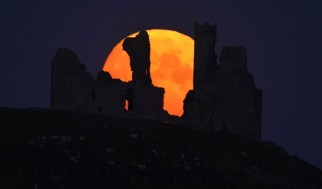 The Sturgeon supermoon, the final supermoon of the year rises over Dunstanburgh Castle in Northumberland