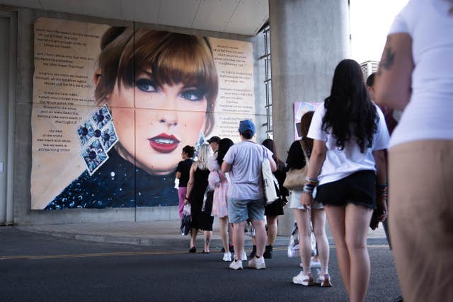 Swifties line up to pose in front of a mural outside Wembley during the Taylor Swift Eras Tour concerts at the venue in 2024 