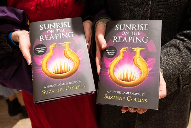 Fans hold copies of the new Hunger Games novel Sunrise On The Reaping by Suzanne Collins