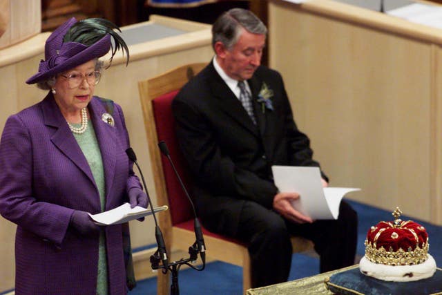 The Queen speaking into a microphone in the original Scottish Parliament building in 1999, with David Steel seated in the background