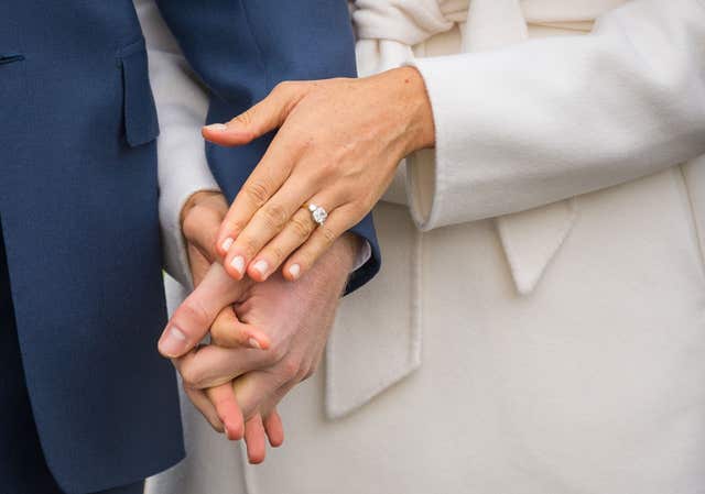 Prince Harry and Meghan Markle, wearing her engagement ring, hold hands at their engagement photocall (Dominic Lipinski/PA)