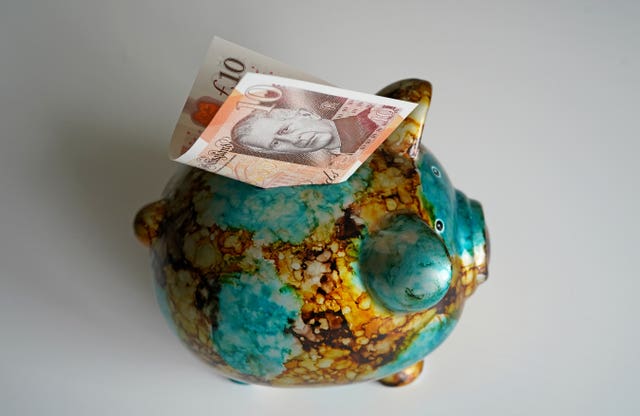 A £10 note sitting on the top of a piggy bank