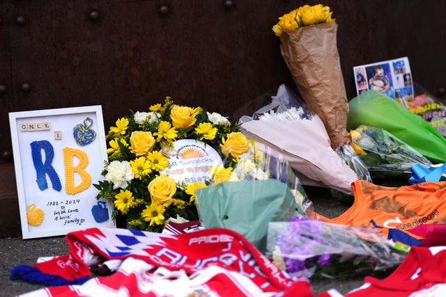 Scarves and flowers on the ground as tributes to Rob Burrow