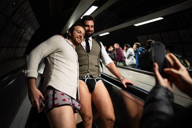 Two men dressed without trousers on the escalator on the London Underground