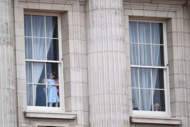 Children look out from from Buckingham Palace as soldiers make their way to the ceremony